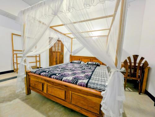 a bedroom with a wooden bed with a canopy at purple villa in Mirissa