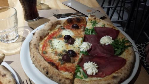 eine Pizza auf einem weißen Teller auf einem Tisch in der Unterkunft Sicily Sea House  in Gioiosa Marea