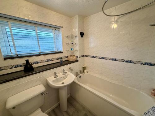a bathroom with a sink and a toilet and a tub at Stylish 3-Bed Family Pet-Friendly Home with Garden in Cardiff