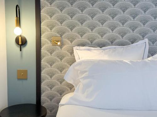 une chambre avec un lit blanc et un mur dans l'établissement Le Palace De Menthon, à Menthon-Saint-Bernard