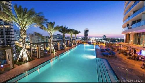 a swimming pool with palm trees on a building at Beautiful Beach front condo with Top Amenities in Hollywood