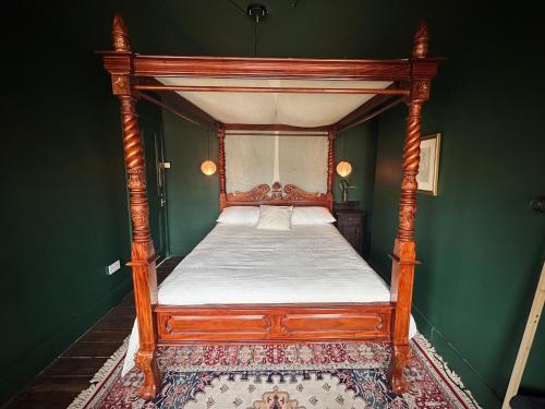 a wooden canopy bed in a green room with a rug at Margate Manor - Rooms by the Sea in Margate