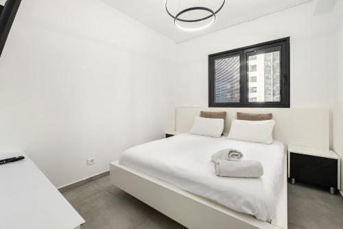 a white bedroom with a white bed and a window at Luxury 4BR Tower w Panoramic Sea View l Mamad in Bat Yam