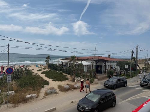 a woman walking down a street next to a beach at Beach Bum Caravan in Caparica