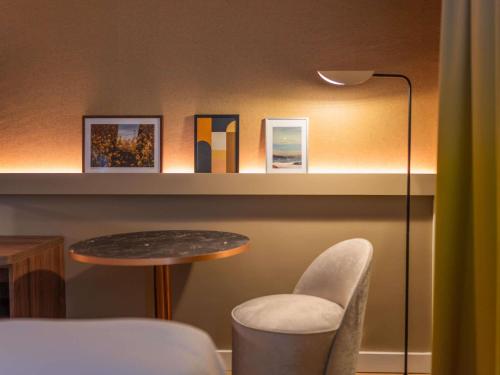 a room with a table and a chair and a lamp at Pullman Toulouse in Blagnac