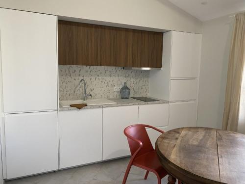 a kitchen with white cabinets and a wooden table at Chez Elsa et Camille in Aigues-Mortes