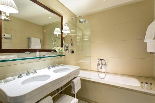a bathroom with a sink, mirror, and bathtub at Gallery Hotel Art - Lungarno Collection in Florence