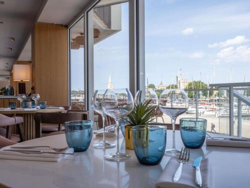 Una mesa con copas de vino y una vista de un puerto. en Mercure La Rochelle Vieux Port, en La Rochelle