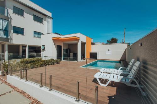 a swimming pool with two lounge chairs next to a building at Apto completo e charmoso para curtir a praia in Itapoa