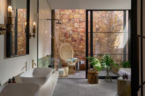 a bathroom with two sinks and a stone wall at The Alexander Estate in Good Hope