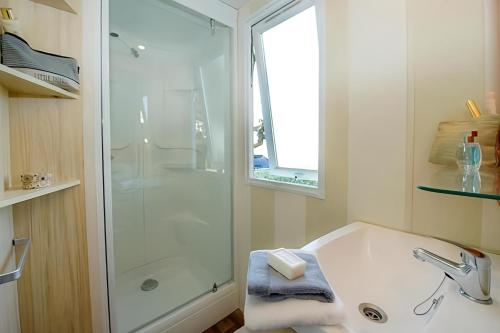 a white bathroom with a shower and a sink at Camping Le Domaine de la Marina in Messanges