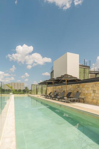 a swimming pool with chairs and a building at Hotel Las Brisas Merida in Mérida