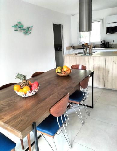 a wooden table with a bowl of fruit on it in a kitchen at Le Petit Bois Vert in Jard-sur-Mer