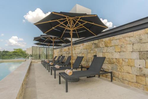 a row of lounge chairs with umbrellas on a patio at Las Brisas Merida in Mérida