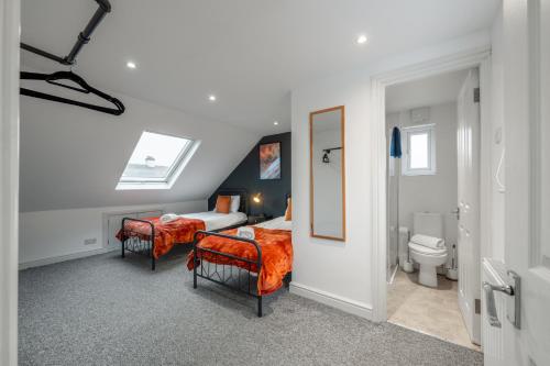 a bedroom with a bed and two chairs and a toilet at Modern Comfort 4BR Home for 10 in North Weald