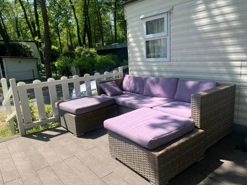a purple couch and ottoman sitting next to a fence at Cozy Mobile Home 'Tante Truus' met privé infrarood sauna - Recreatiepark 't Veluwshof - VELUWE in Hoenderloo