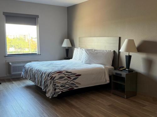 a bedroom with a bed and two lamps and a window at Red Roof Inn La Porte in La Porte