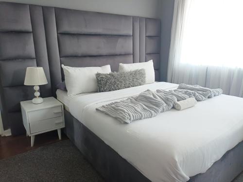 a bedroom with a large white bed and a window at KHAHILIGI Guest House in Roodepoort