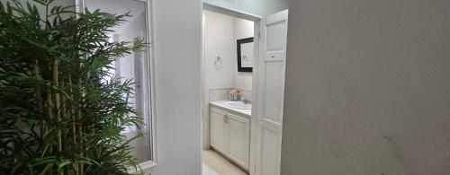 a white bathroom with a sink and a mirror at Atelier Fleur in Diego Martin
