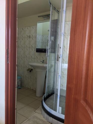 a bathroom with a shower with a sink and a toilet at Glory Motel by HODAC LTD in Kigali