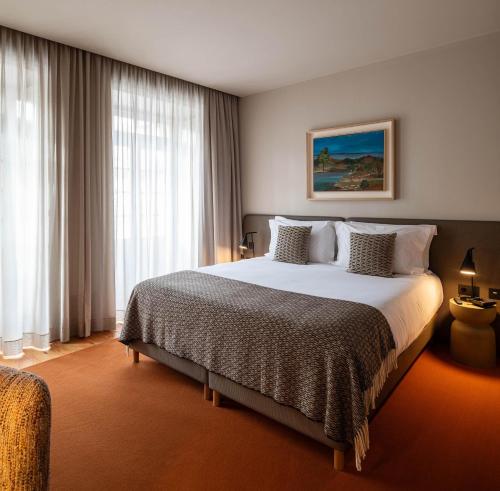 a bedroom with a large bed and a large window at Casa Zogbi Hotel in Porto