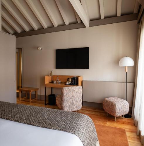 a hotel room with a bed and a desk and a tv at Casa Zogbi Hotel in Porto