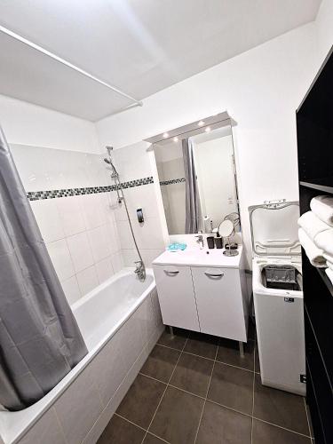 a white bathroom with a tub and a sink at Studio Europarc Créteil - 2mn Métro 8 - Paris in Créteil