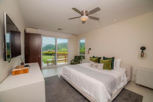 une chambre avec un grand lit avec un ventilateur de plafond dans l'établissement Montecielo 3E 3bdrs ocean view in Los Suenos, à Herradura