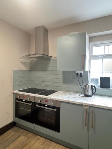 a kitchen with a stove and a counter top at En-suite studios near Wembley Stadium in Northwood
