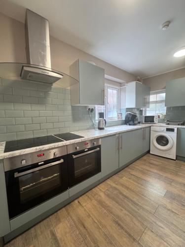 a kitchen with a stove and a dishwasher at En-suite studios near Wembley Stadium in Northwood
