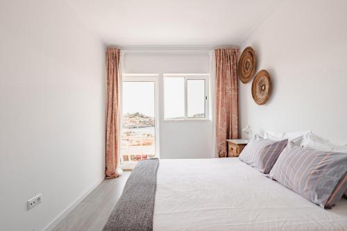 a white bedroom with a large bed and a window at Vegan Apartment - Porto e Douro in Bandeira