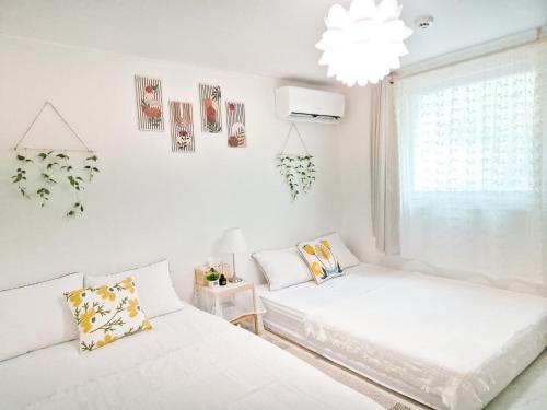 two beds in a white room with a window at Stay Ok - Amsa Station 암사역도보2분 KSPO LOTTEWORLD 올림픽경기장 롯데월드 롯데타워 아산병원 in Seoul
