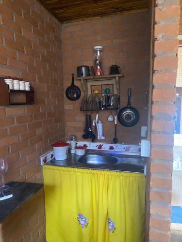 a kitchen with a sink and a brick wall at O Chalé de Rita in Lima Duarte