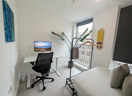 a bedroom with a desk with a computer and a chair at Modern & charming home in Hackney in London