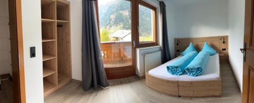 ein Schlafzimmer mit einem Bett mit blauen Kissen und einem Fenster in der Unterkunft Haus Gamskogl in Neustift im Stubaital