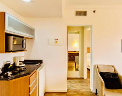 a kitchen with a counter top and a living room at Studio Completo - Vila Olímpia - Moema in Sao Paulo