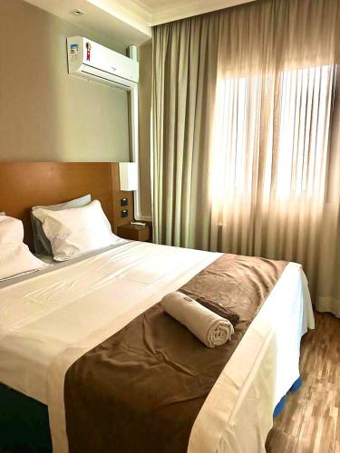 a large bed in a hotel room with a window at Studio Completo - Vila Olímpia - Moema in São Paulo