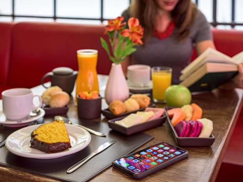 a woman sitting at a table with a plate of food at Mercure Sao Paulo Alamedas in Sao Paulo