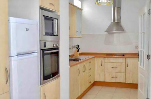 une cuisine avec des appareils électroménagers blancs et des armoires en bois dans l'établissement Apartamento centrico familiar, à Santa Cruz de Tenerife