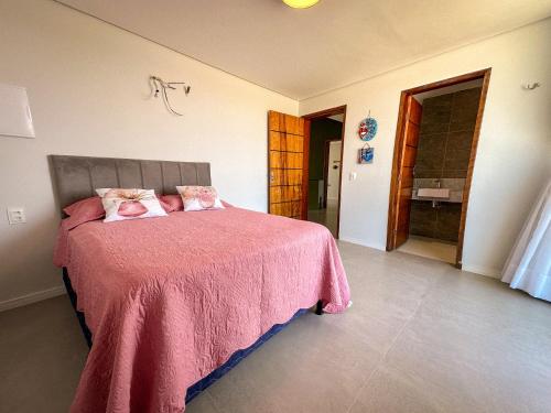 a bedroom with a bed with a pink bedspread at Casa Som das Ondas in Fortim