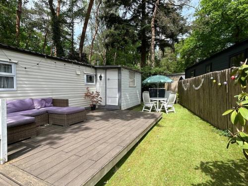 a patio with a purple couch on a wooden deck at Forest Cabin - Waldhütte Tante Truus Veluwe - Recreatiepark 't Veluwshof in Hoenderloo