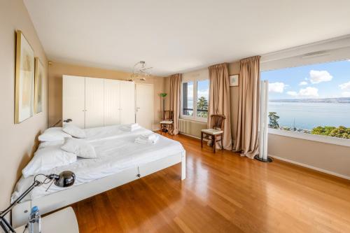 a bedroom with a large white bed and a large window at Villa heart of Evian swimming pool in Évian-les-Bains