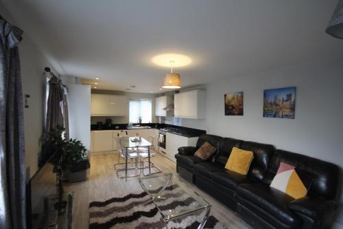 a living room with a black leather couch and a kitchen at Holden Court Apartments -Apt 4 in West Drayton