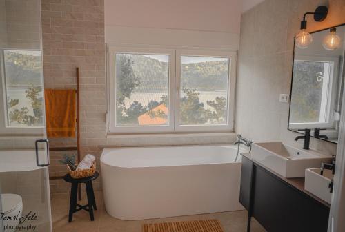ein Badezimmer mit einer Badewanne und einem Waschbecken sowie zwei Fenster in der Unterkunft Discover Lastovo premium accommodation in Skrivena Luka