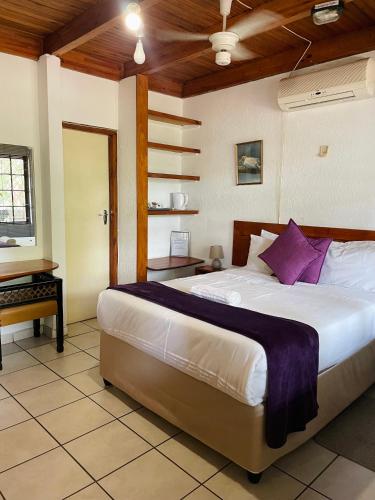 a bedroom with a large bed with purple pillows at North Coast Gateway Hotel in KwaMbonambi