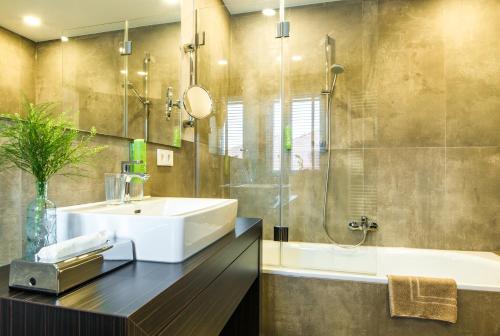 a bathroom with a sink and a shower and a tub at Strandhotel Luv in Timmendorfer Strand