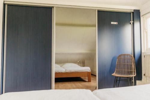 a bedroom with a sliding glass door with a bed and a chair at Vakantiehuisje met ruime tuin en hottub in Ouddorp