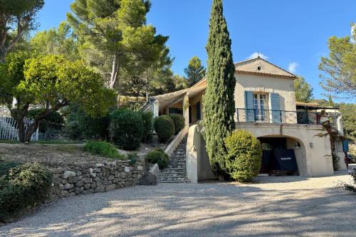 a house with a stone wall and a tree at Family Home in the Heart of the Luberon with Swimming Pool and Panoramic Vi in Mérindol