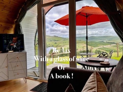 an open glass door to a patio with an umbrella at Forester's Retreat Glamping - Dinas View - Vaccinated dogs over the age of 2 are accepted in Aberystwyth