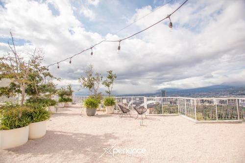 einen Balkon mit Stühlen und Pflanzen auf einem Gebäude in der Unterkunft Sunflower at 12, City Views and Wonderland Vibes! in Hatillo